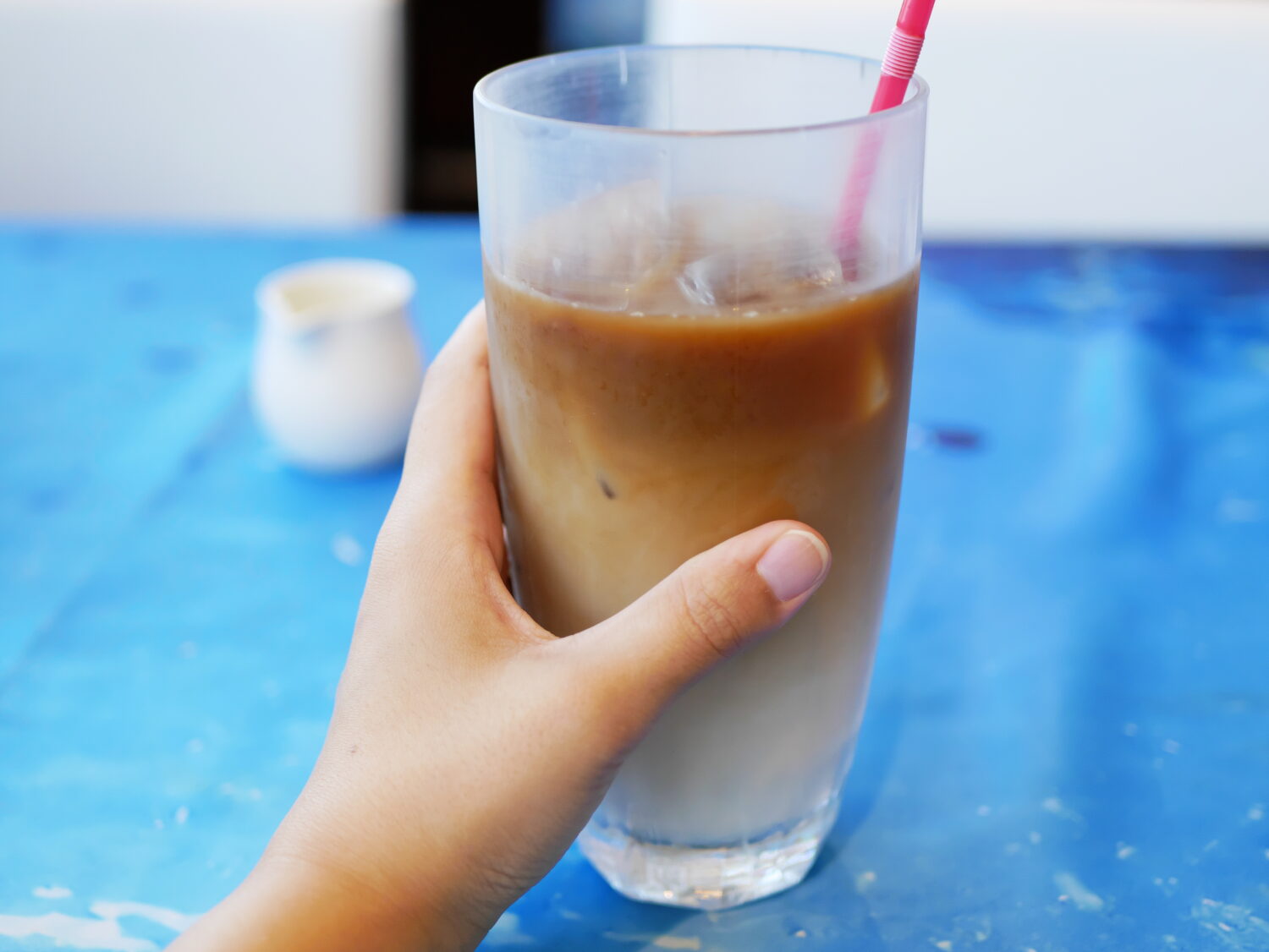 すなば珈琲のアイスカフェオレのグラスを持った様子