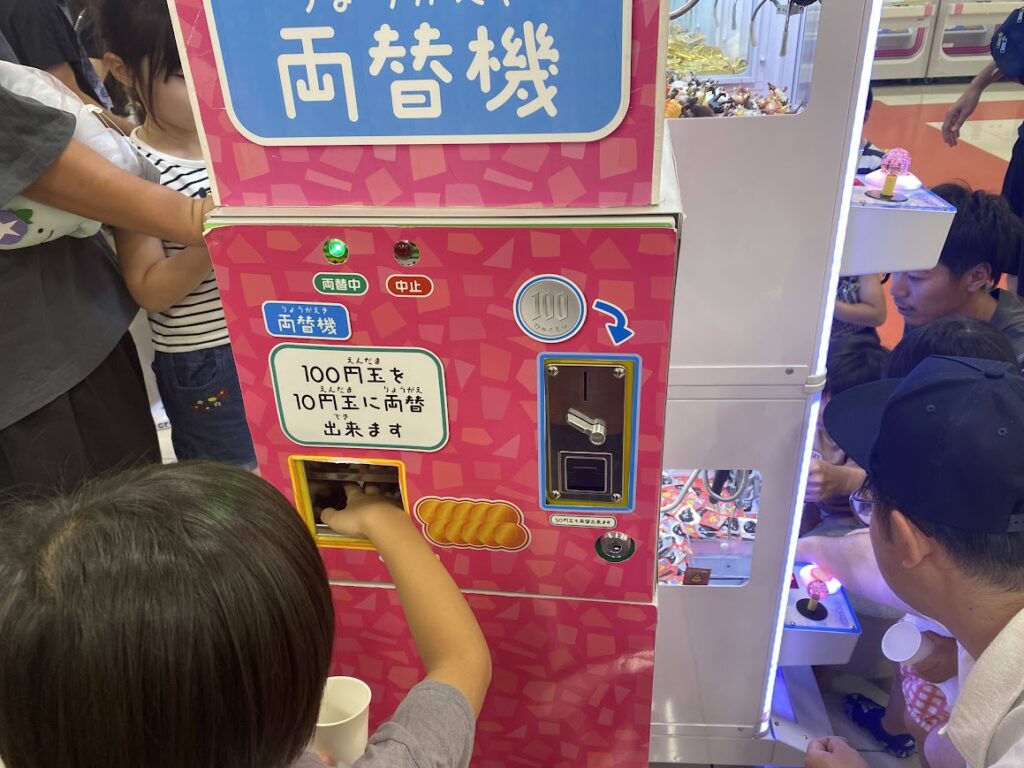 100円玉の両替機で両替をする子ども