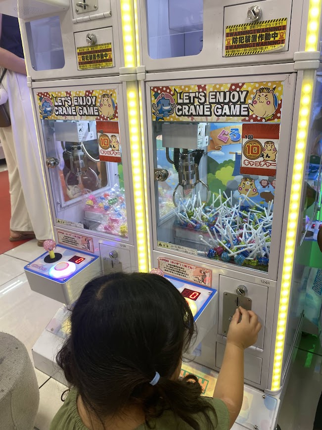 チュッパチャップスのクレーンゲームにお金を入れる子ども