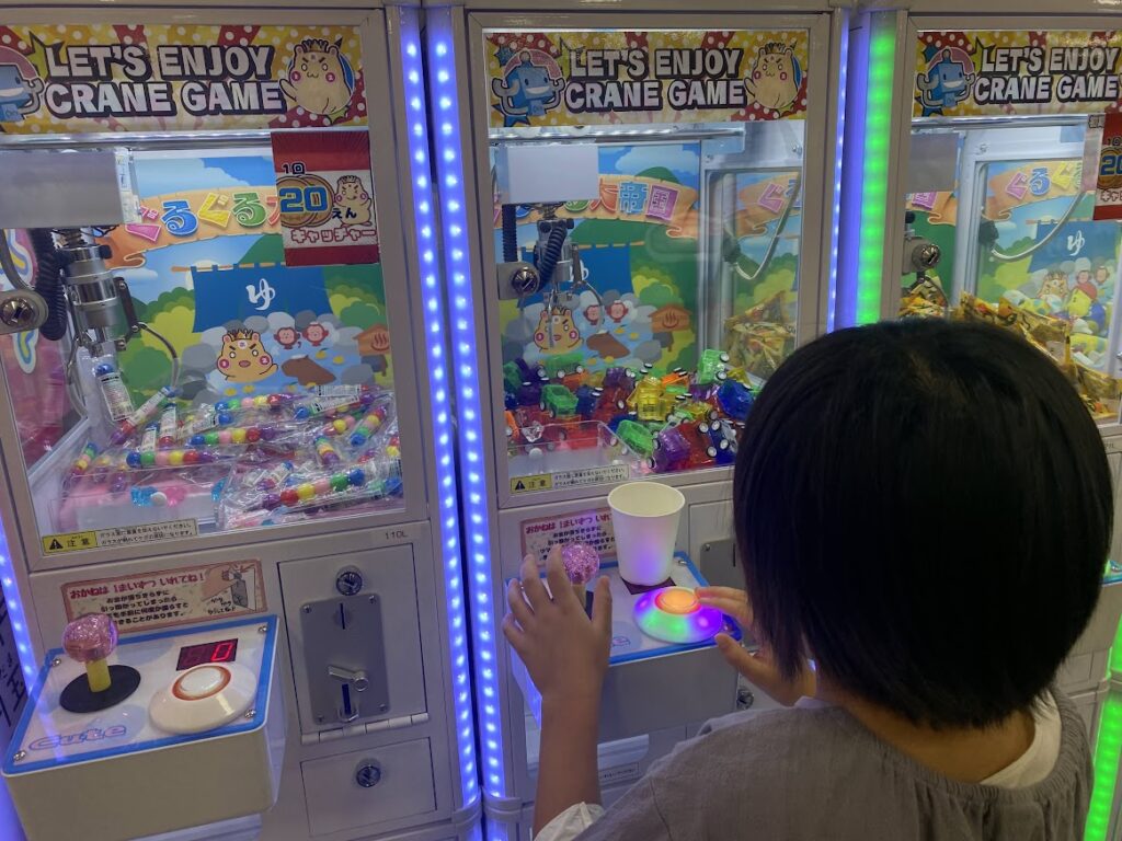 車のおもちゃのクレーンゲームに挑戦する子ども