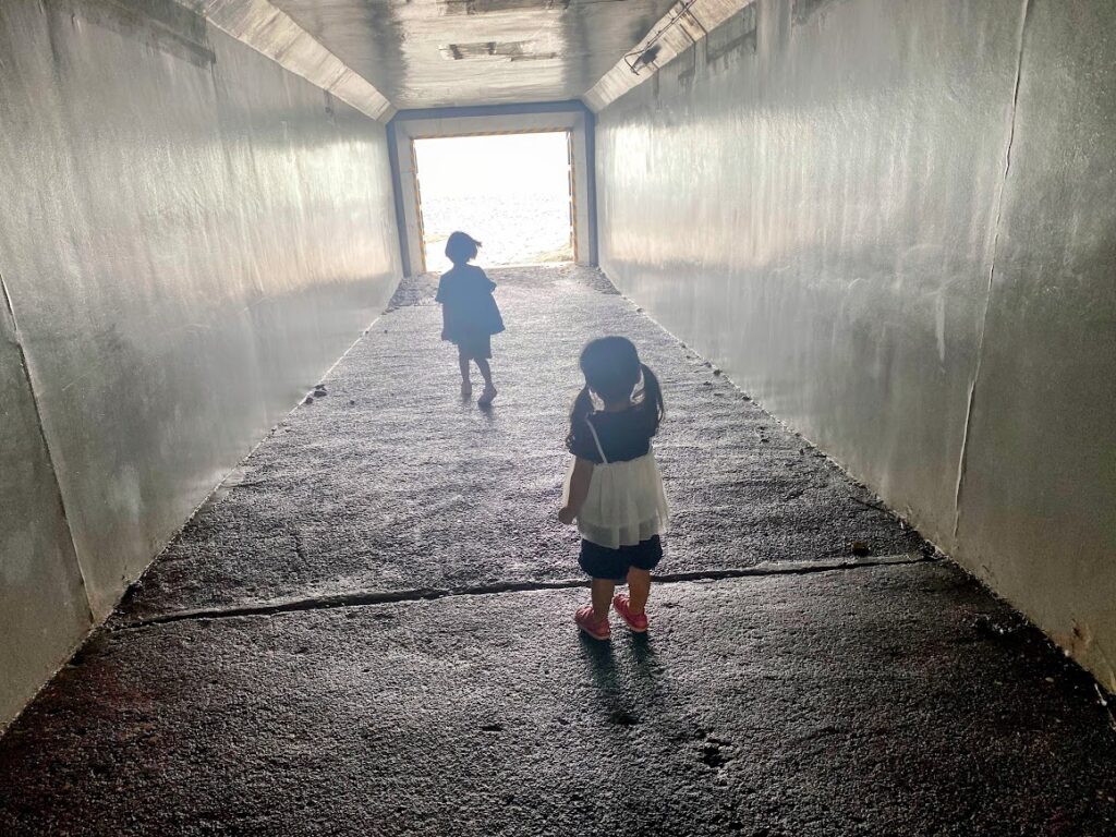 海へとつながるトンネルの中を歩く子ども2人