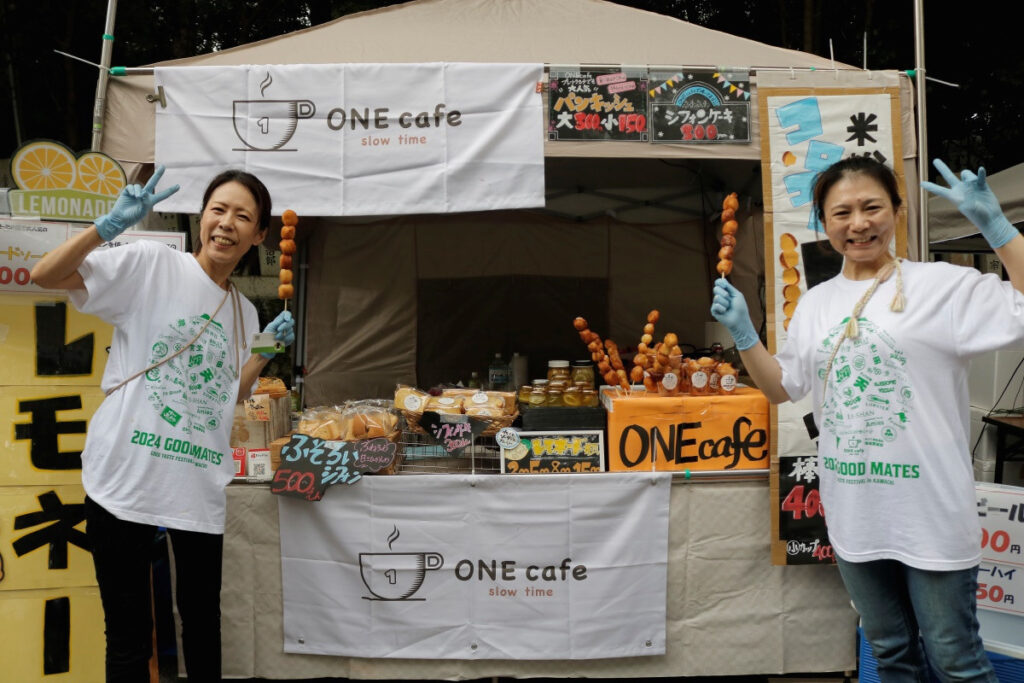 河内おいしいもん市2024－ONE cafe：米粉ドーナツ串を片手に笑顔を見せてくれたオーナー様たち