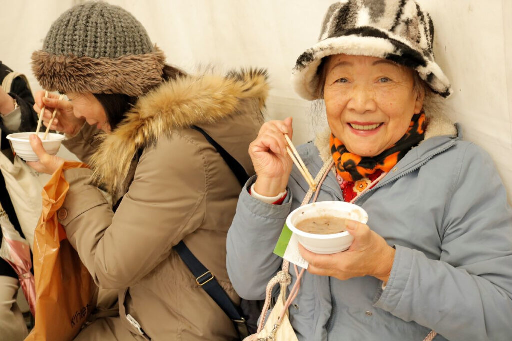 粥占神事（枚岡神社）｜小豆粥を食べる参拝者の女性