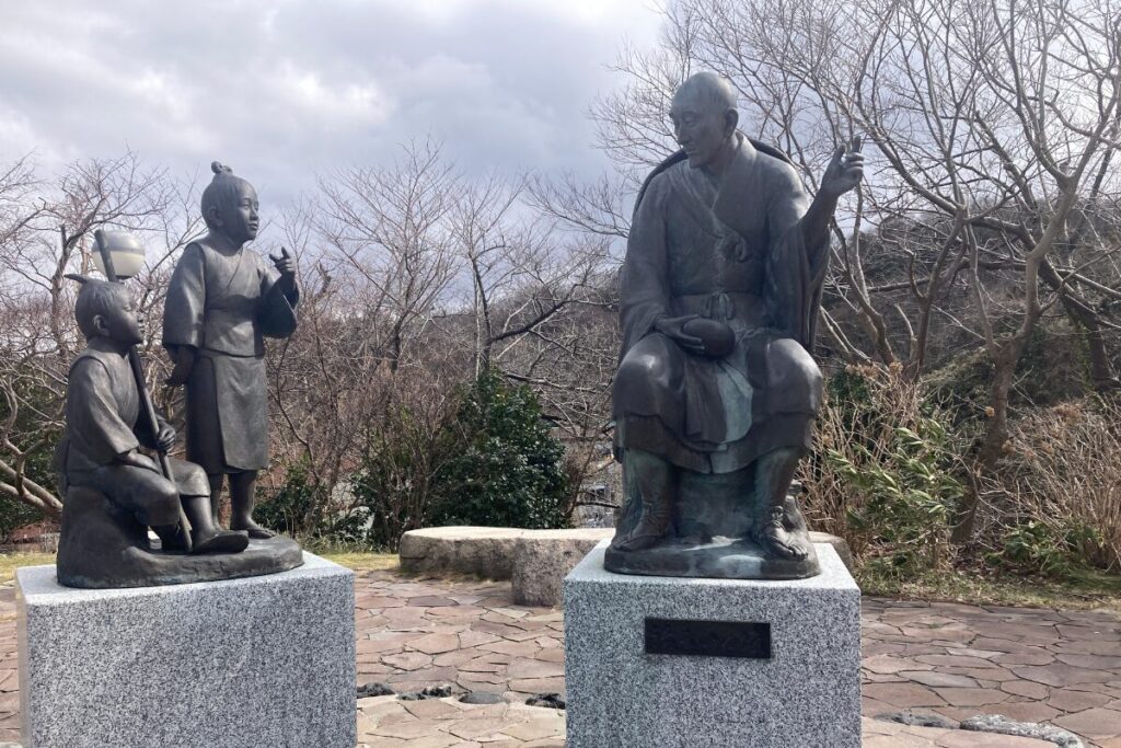 左側に小さい子どもが2人、右側に良寛さんが左手を広げて語りかけている様子の銅像が建っています。