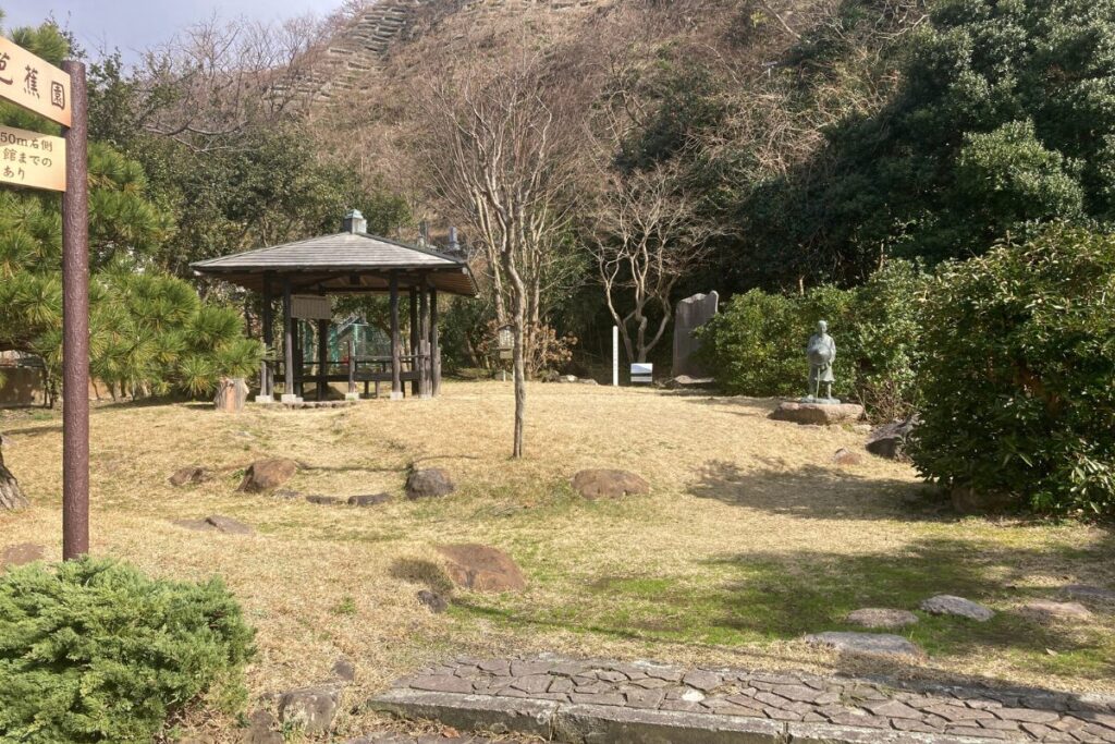 公園の写真です。奥の方に屋根のあるベンチが置かれています。