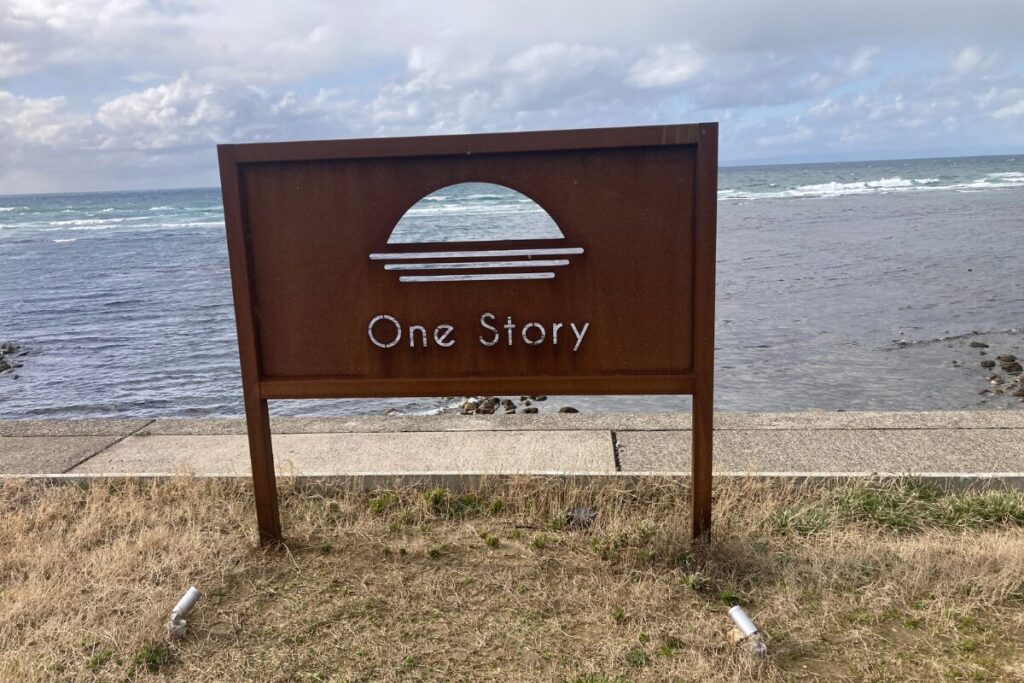 One Storyと書かれた看板です。奥に海が見えます。