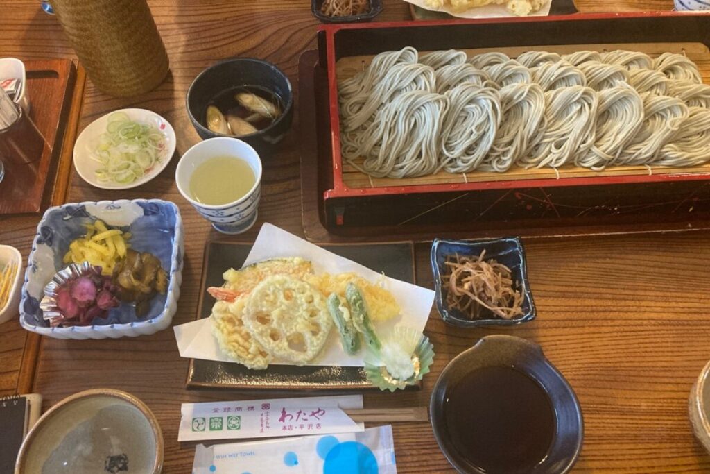 へぎそば、南蛮かもだし、輪切りネギ、漬物、天ぷら、きんぴら、そばつゆが並んでいます。