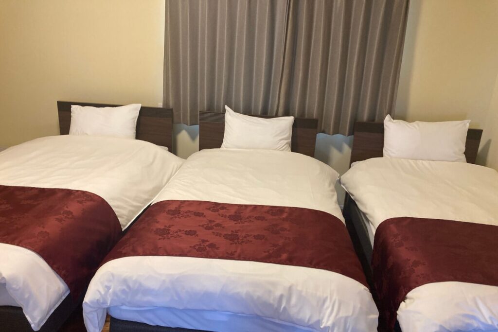 シングルサイズのベッドが3つあります。赤い帯がかかっています。