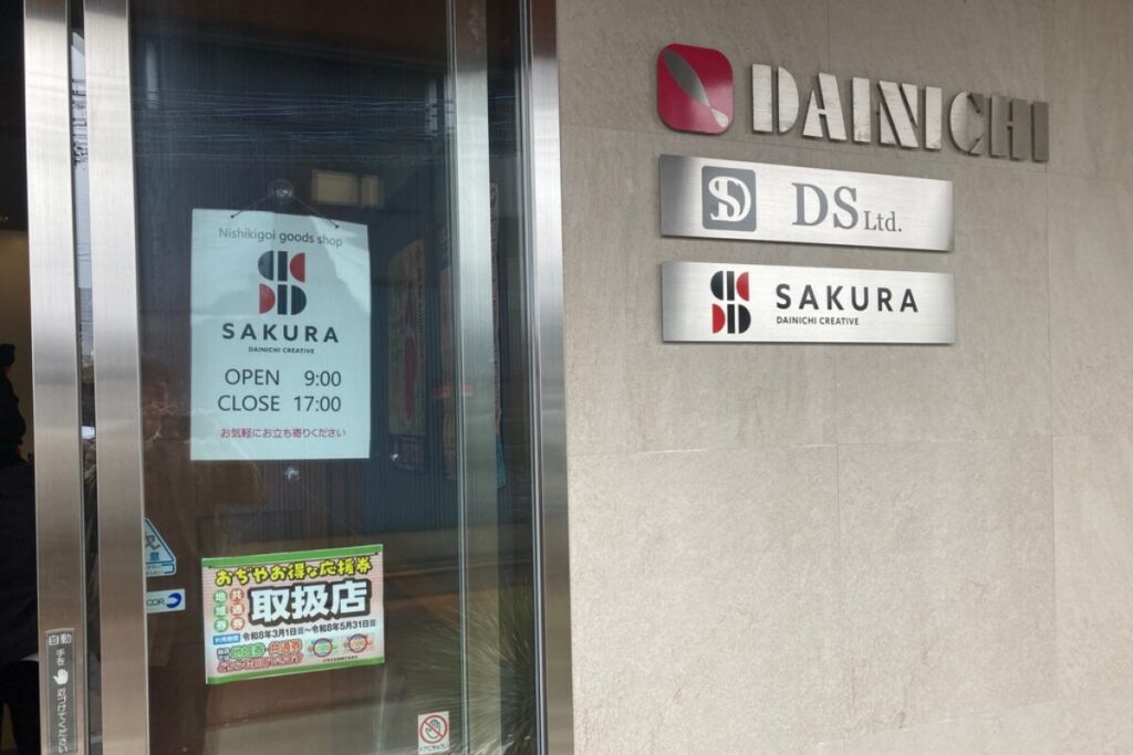 自動ドアがあり、ガラスに「SAKURA OPEN 9:00 CLOSE 17:00」と記された紙が吊るされています。