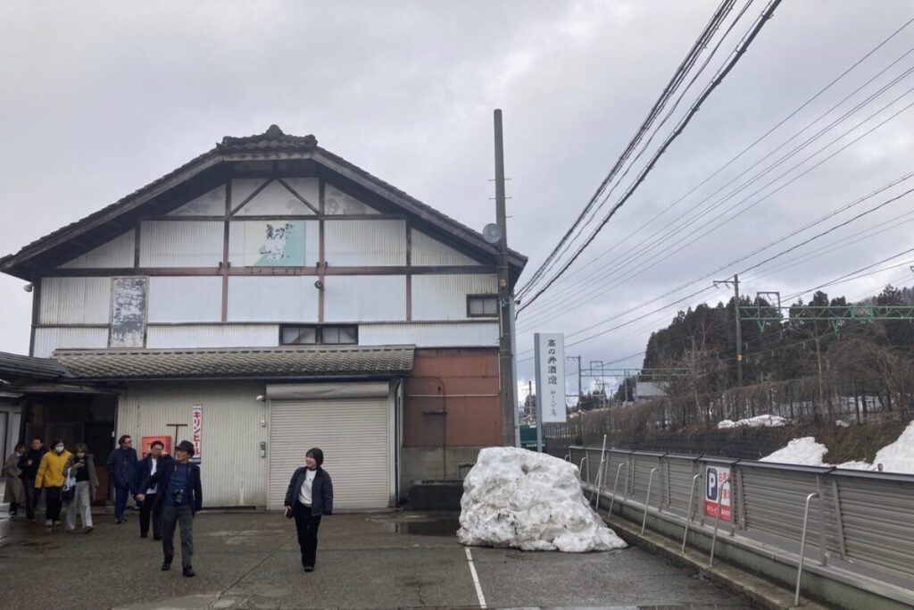曇り空の下に倉庫があります。右側には線路があります。