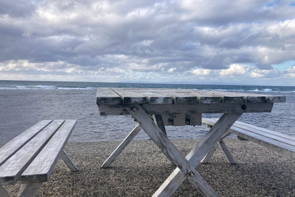日本海と曇り空をバックにテーブルとベンチをアップで映しています。