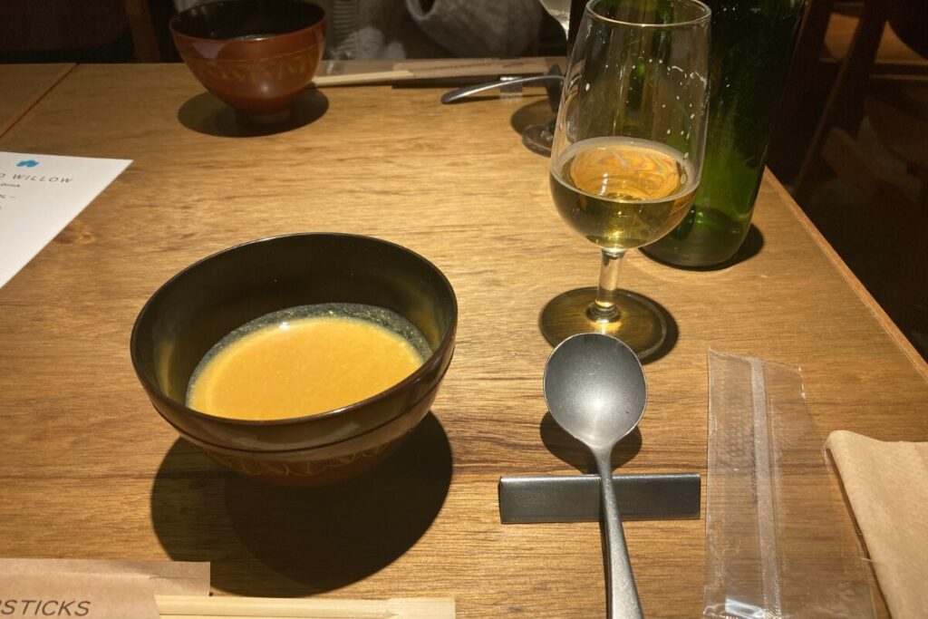 野菜スープとビールが注がれたワイングラスが写っています。