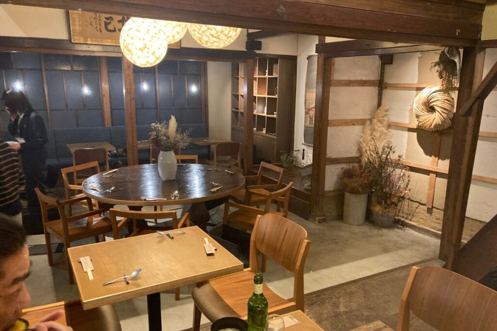 レストランの店内が写っています。天井には和風なシャンデリアがあり、木製の棚や壁、仕切り、椅子とテーブルが写っています。