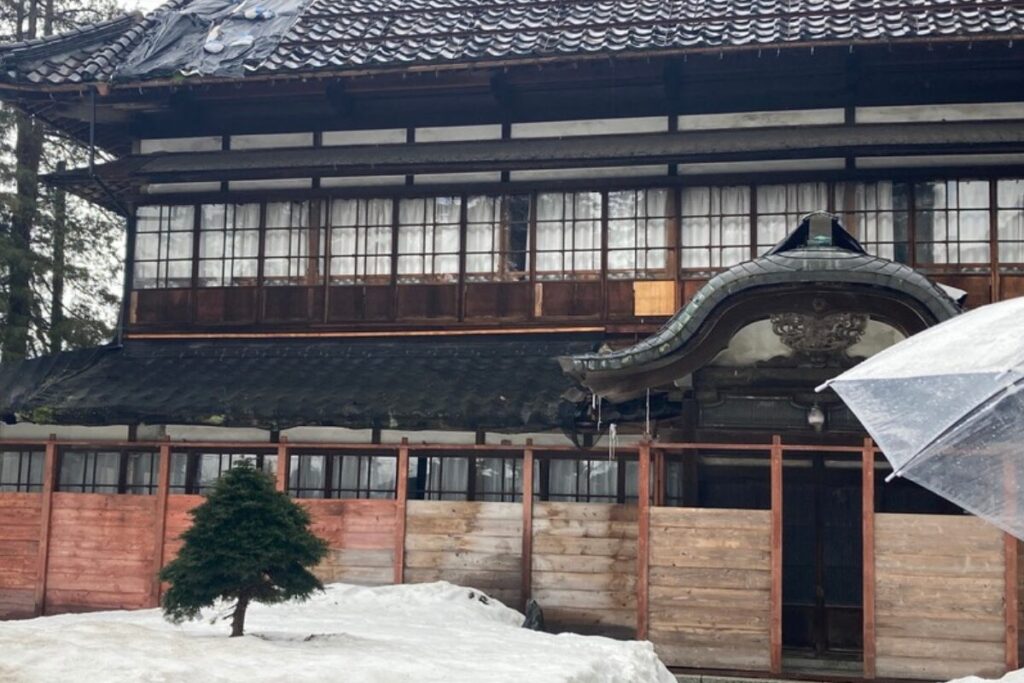 大きな木造の邸宅の玄関が写っています。