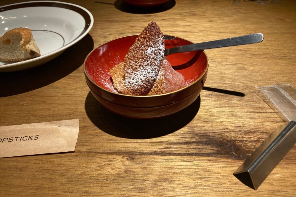 楕円形で茶色いお菓子と薄ピンクの果物が入った皿です。