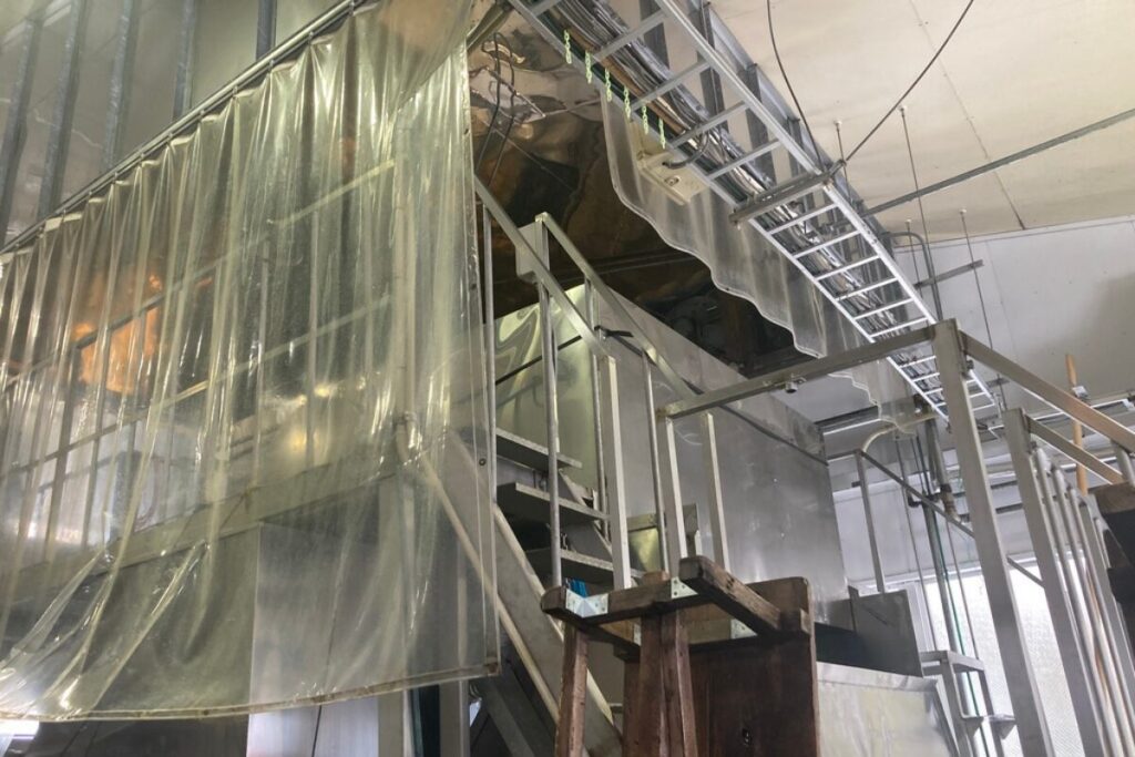 大きな機械が写っています。上部には梯子のような鉄製の物体があり、ところどころに階段が見えます。