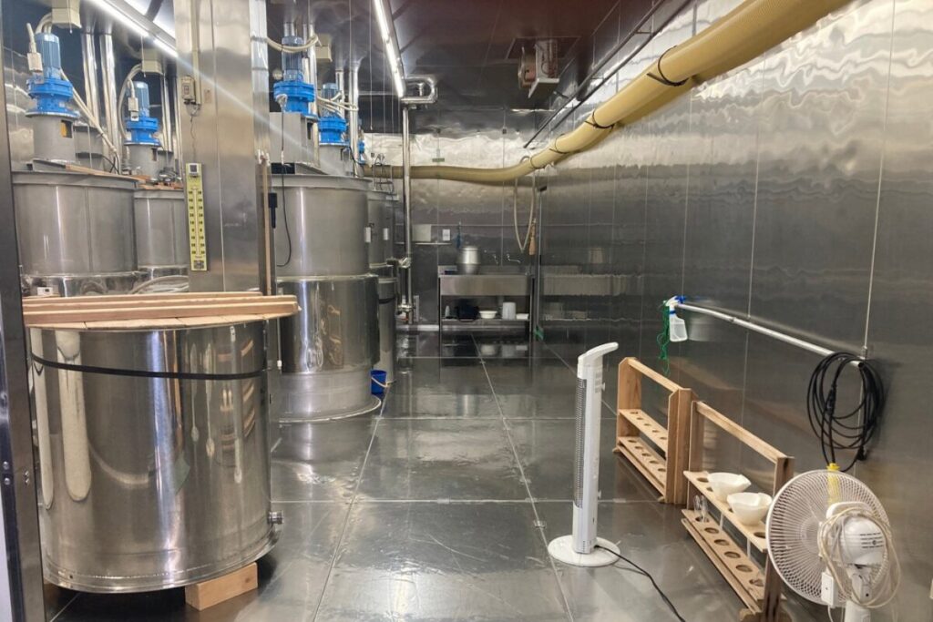 銀色の壁と床の部屋で、木製の蓋をされた寸胴がいくつも置かれています。