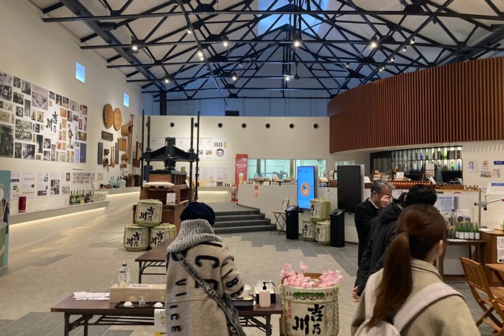 お酒の販売をしている屋内スペースで、左の壁には吉乃川のポスターが貼らられています。奥にはカウンターがあります。