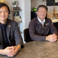 男性が2人、並んで座っています。