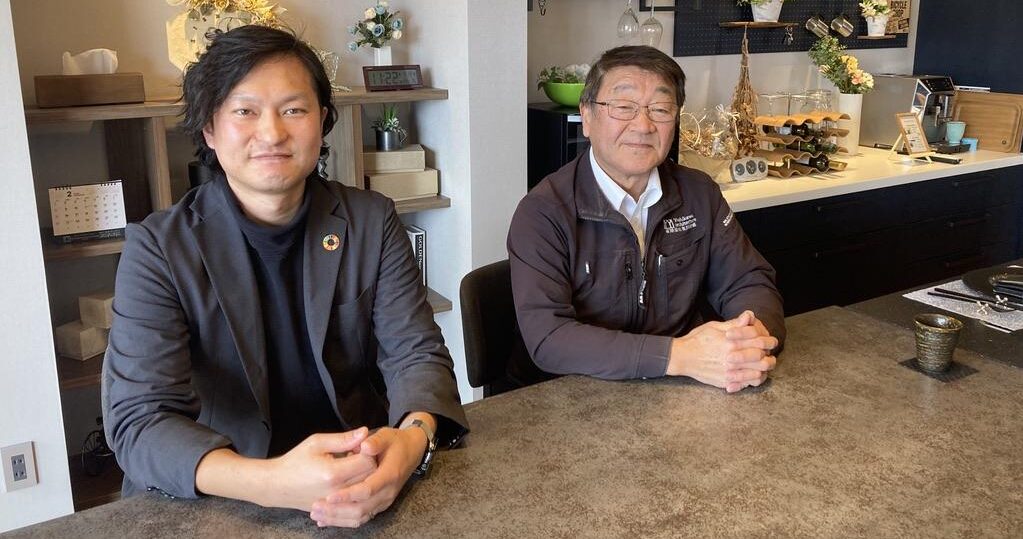 男性が2人、並んで座っています。