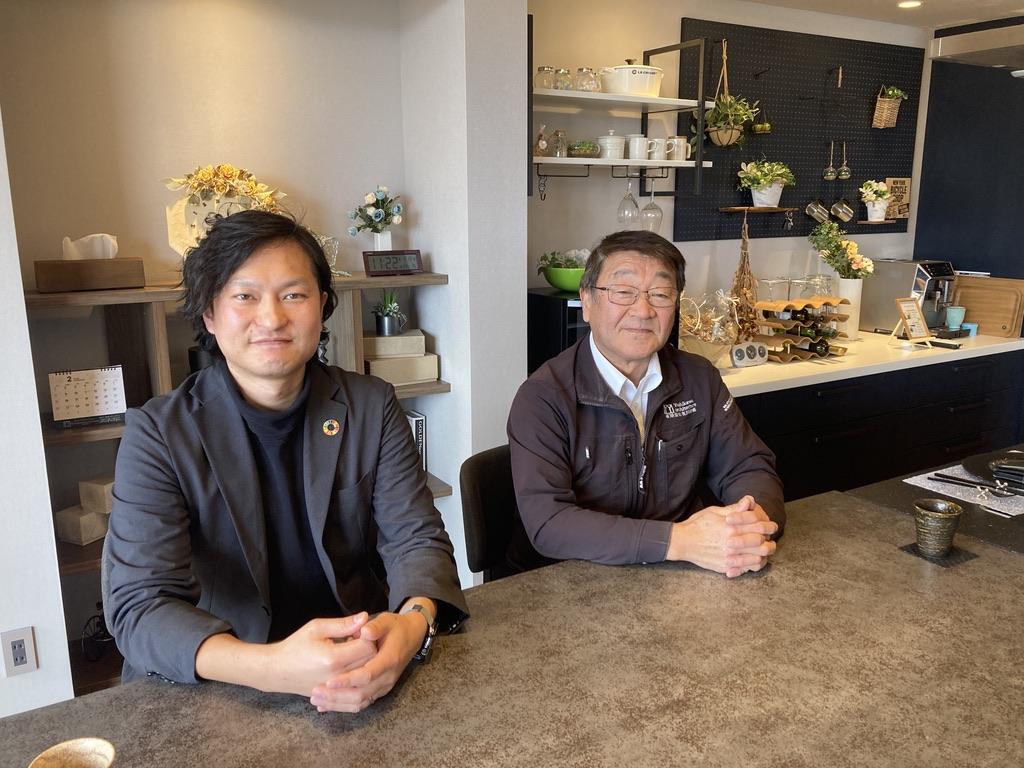 男性が2人、座った姿勢で写っています。