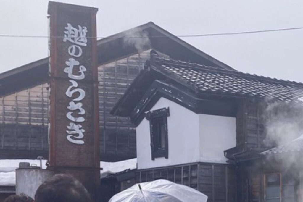 「越のむらさき」と書かれたレンガづくりの煙突が写っています。