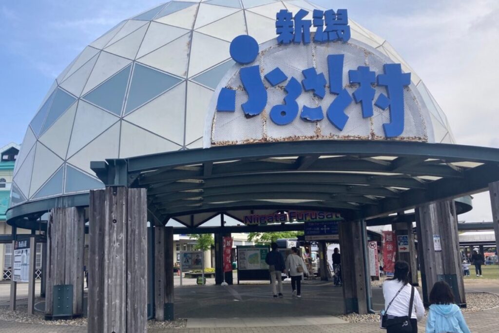 アーケードのある広場で、屋根に「新潟ふるさと村」という文字が書かれています。