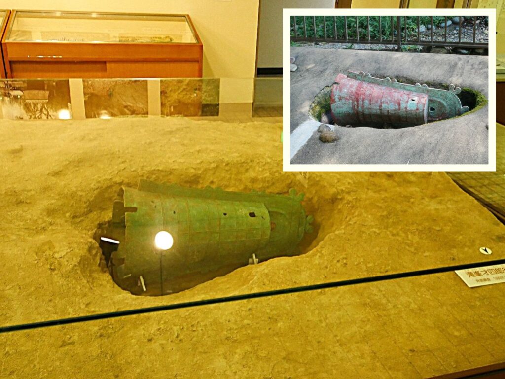 フロア内中央に設置されている滝峯才四郎遺跡に埋まっていた銅鐸の様子(右上:どうたく公園内にある出土の様子を再現したもの)