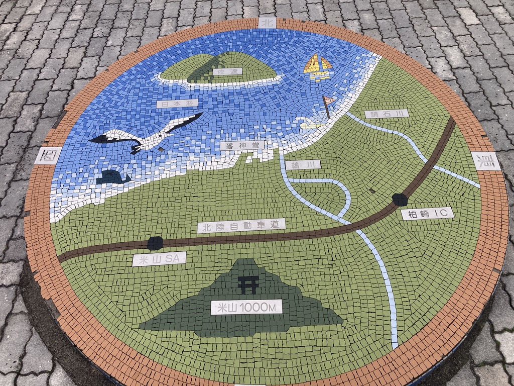 北陸自動車道と日本海と佐渡を示した簡単な地図が円形のレンガに描かれています。