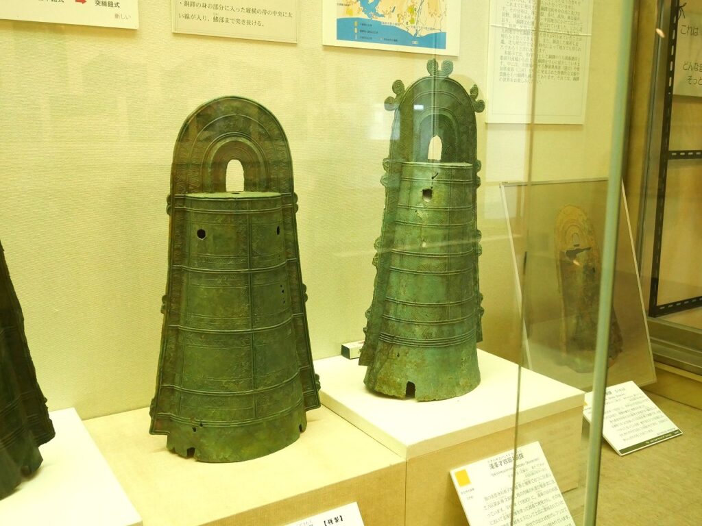 左:三遠式の前原銅鐸(複製)、右:近畿式の滝峯才四郎谷銅鐸