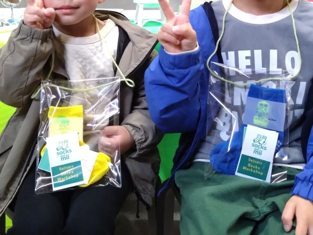 ラッピングされた靴下をぶら下げてピースする子供たち