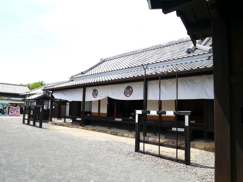 冠木門から見た関所内（右側手間から本番所、御制札場、姫様館（ひめさまやかた）と顔ハメ看板。顔ハメ看板の後ろの建物は隣接する田園空間博物館総合案内所のもの）