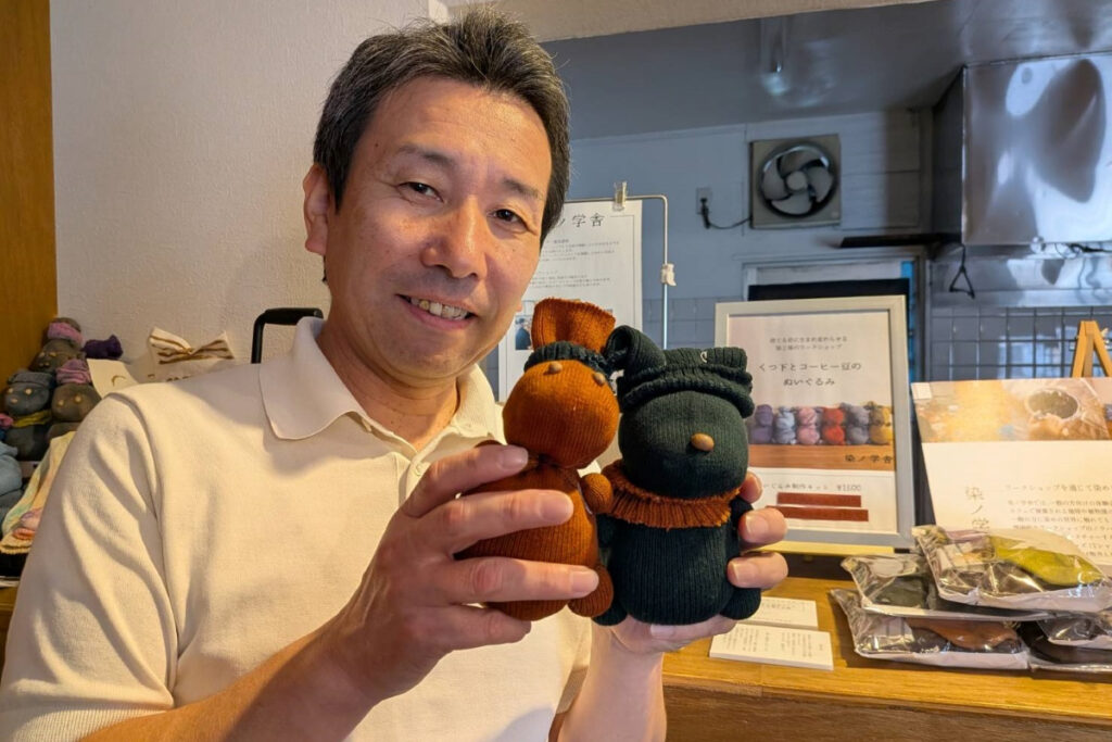 福井プレスーくつ下とコーヒー豆のぬいぐるみを手に持つ福井社長